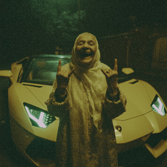 Person in a costume making a gesture in front of a yellow sports car at night.