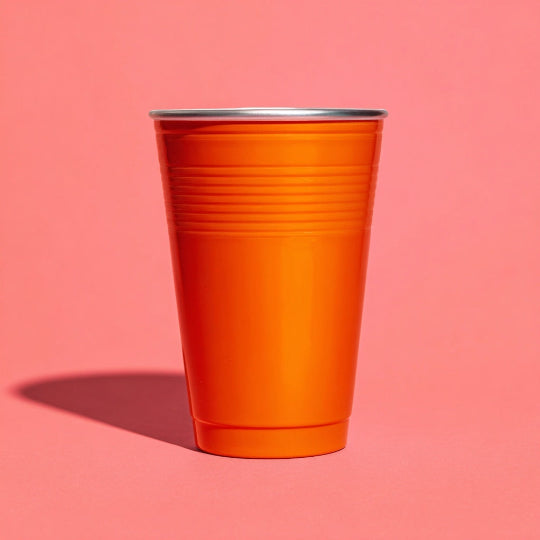 Orange plastic cup on a pink background