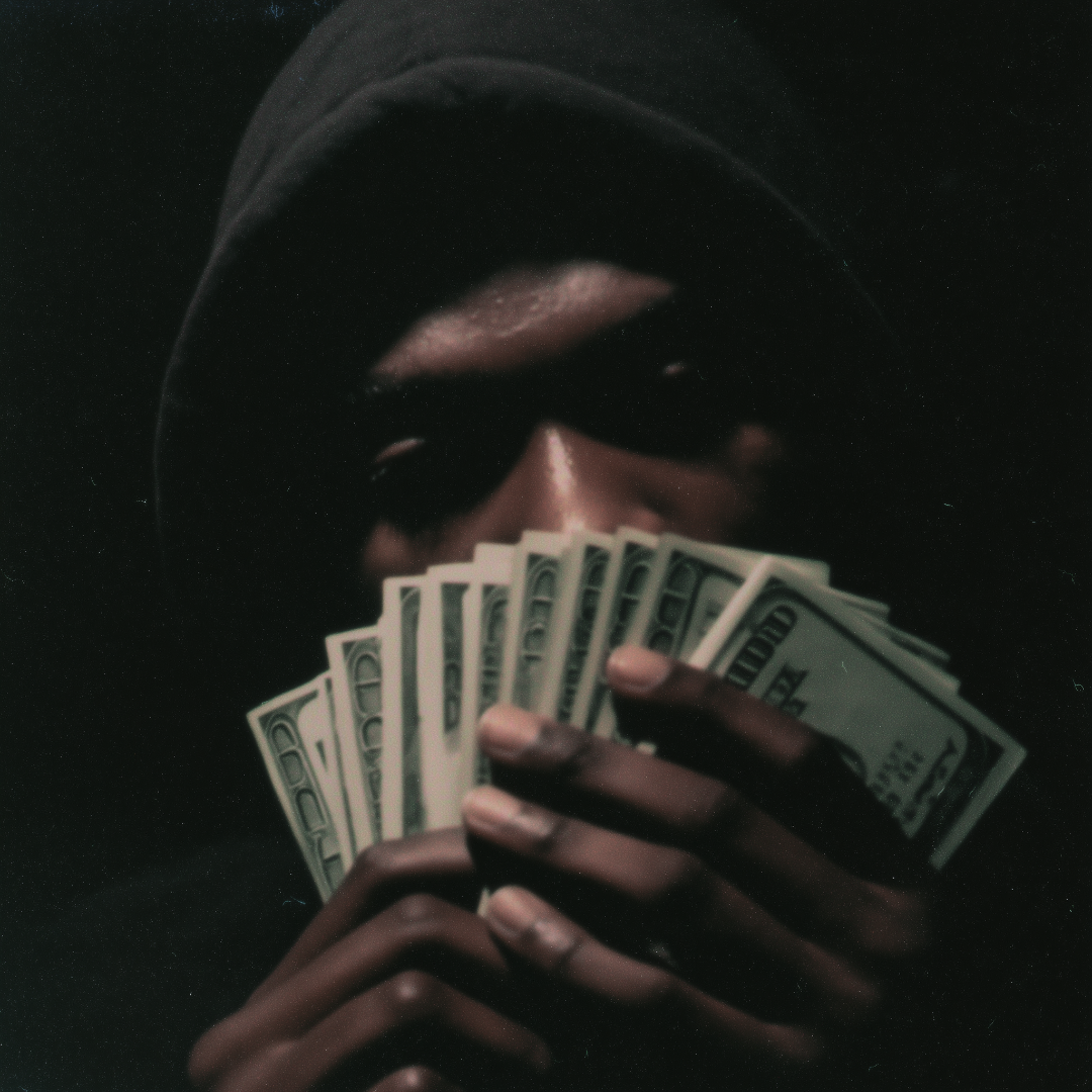 Person holding a fan of money against a dark background