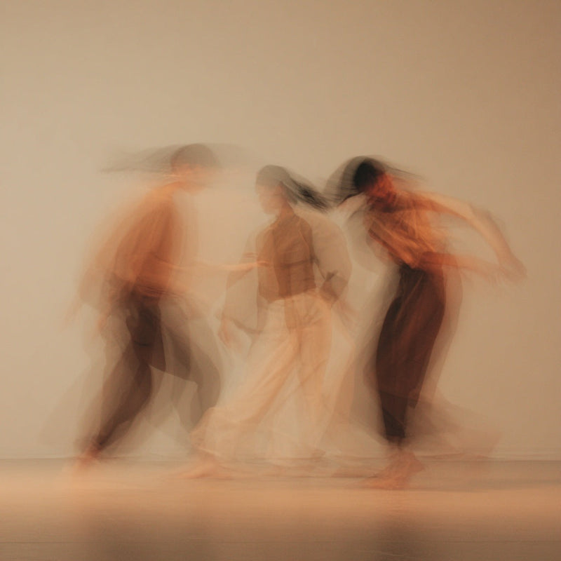 Blurred image of three people in a line with a neutral background