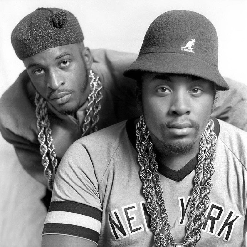 Two men wearing bucket hats and chains, one with a 'New York' jersey.