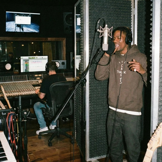 Person in a recording studio with microphones and audio equipment.