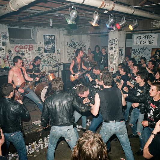 Live band performing on stage with an audience in a room with graffiti-covered walls.