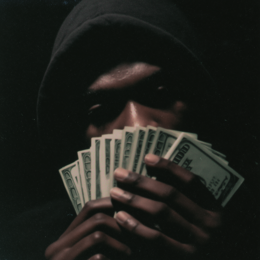 Person holding a fan of money against a dark background