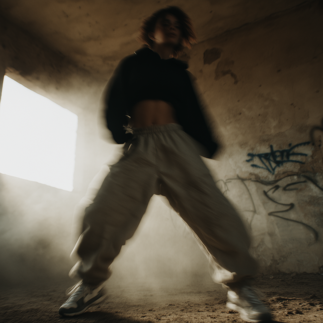 Person in a dark, graffiti-covered room with a light source creating a dramatic effect.